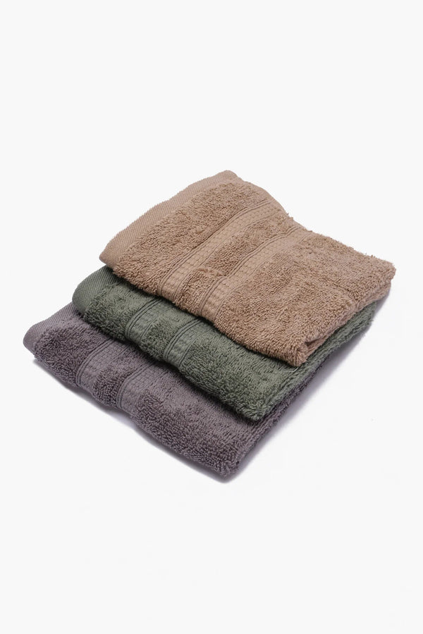 Stack of three cotton towels in brown, green, and gray on white background