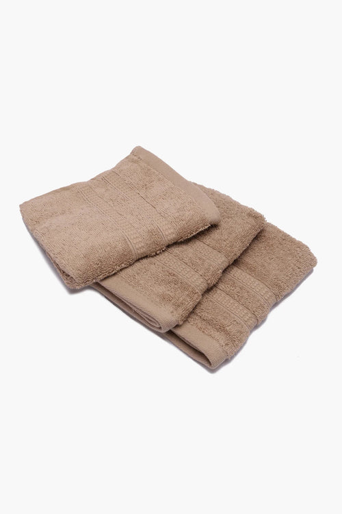 Set of three beige cotton towels neatly folded on a white background