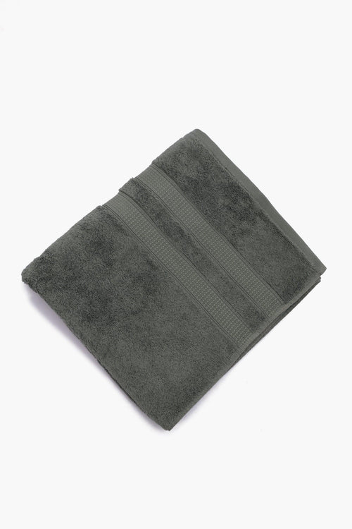 Folded dark grey cotton towel with textured stripes on white background
