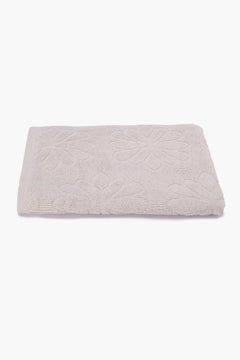 Folded beige cotton towel with floral textured pattern on a white background