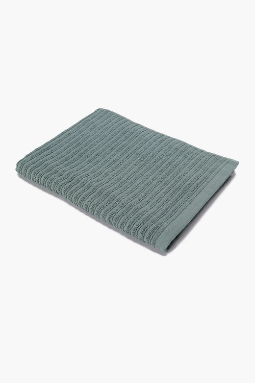 Folded green textured cotton towel on a white background
