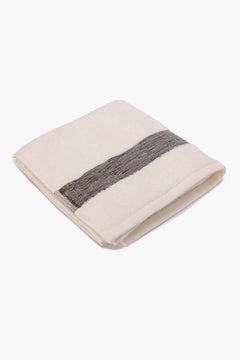 Folded cream cotton towel with grey decorative stripe on white background