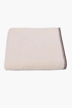 Folded white cotton towel with brown stitched edge on white background