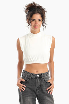 Woman wearing a sleeveless white cropped top with high-waisted black jeans