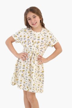 Smiling girl wearing a short-sleeve cotton dress with banana print, hands on hips