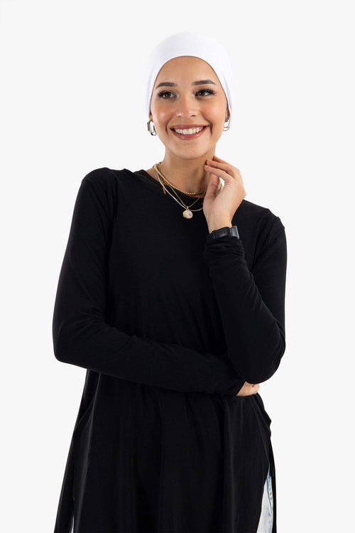 Smiling woman in a black long-sleeve top and white headscarf, modest fashion style