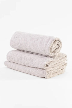 Set of three rolled beige cotton towels with textured pattern on white background