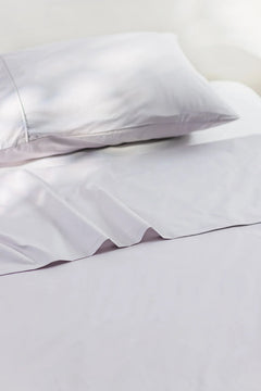 Soft white cotton pillowcase and bedsheet set, neatly arranged on a bed