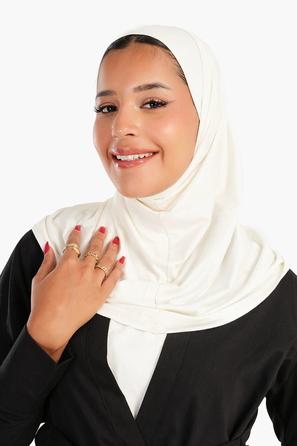 Woman in white cotton hijab and black abaya, smiling, wearing gold rings, modest fashion