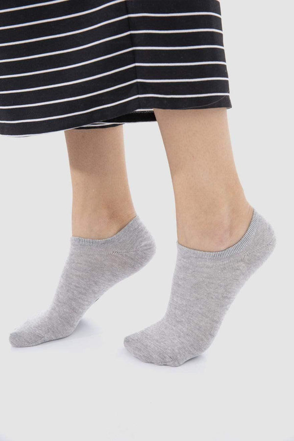Woman wearing soft grey cotton ankle socks with a striped skirt on a light background