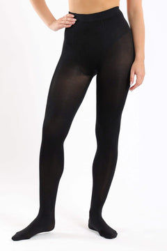 Woman wearing opaque black pantyhose, hands on hip, against white background