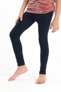 Girl wearing black cotton leggings and a pink top on a white background