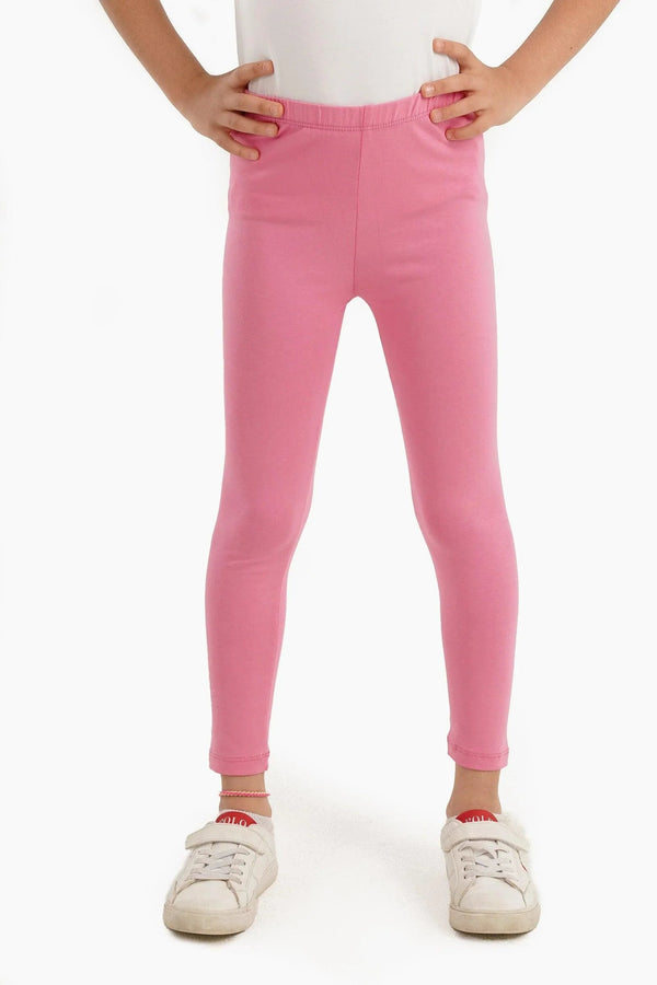 Girl wearing pink long leggings and white sneakers on white background