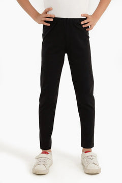 Girl wearing black long leggings and white sneakers, hands on hips, studio background