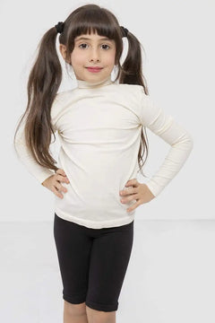 Girl wearing black knee-length shorts and a cream long-sleeve top on white background