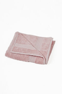 Folded pink cotton towel with textured border on white background