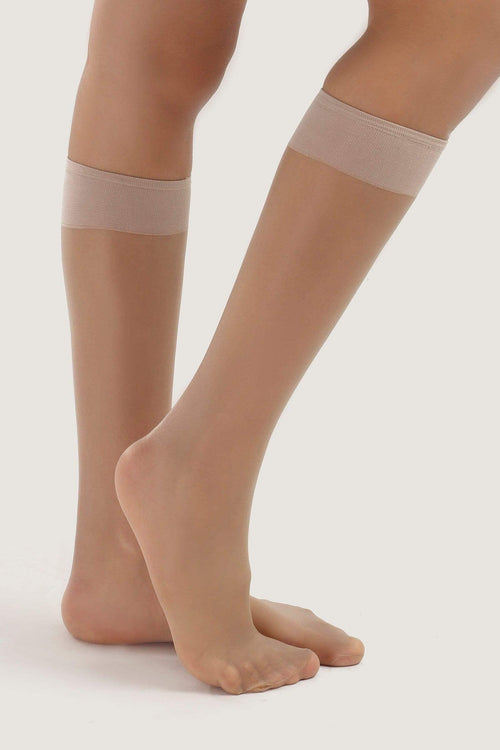 Sheer nude knee-high socks with wide elastic band on model, feminine hosiery style